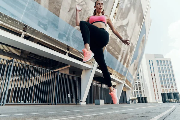 Vista de ángulo bajo de la joven confiada en ropa deportiva corriendo al aire libre —  Fotos de Stock