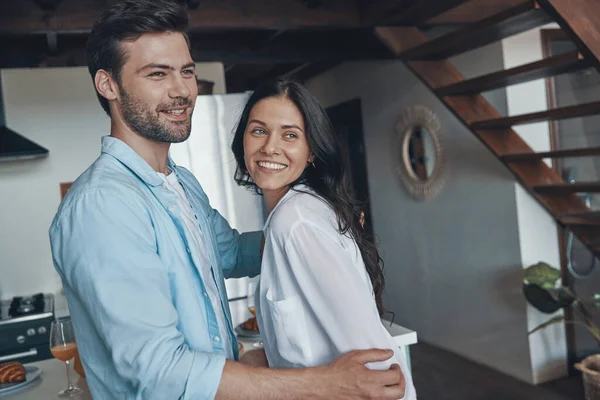 Hermosa pareja joven sonriendo y vinculándose mientras pasa tiempo en la cocina — Foto de Stock