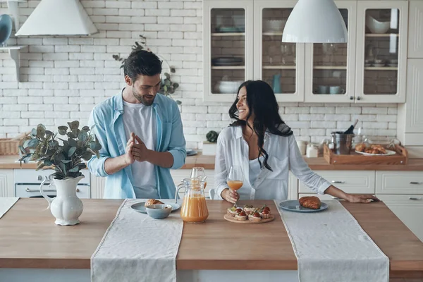 Šťastný mladý pár připravuje snídani společně, zatímco tráví čas v domácí kuchyni — Stock fotografie
