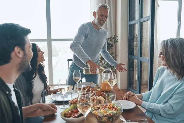 Happy multi-generation family communicating and smiling while having dinner together — Stock Photo, Image