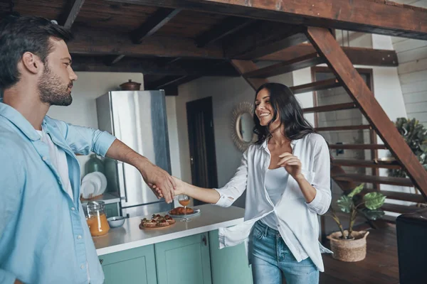 Gyönyörű fiatal pár mosolyog és táncol, miközben időt töltenek a konyhában. — Stock Fotó