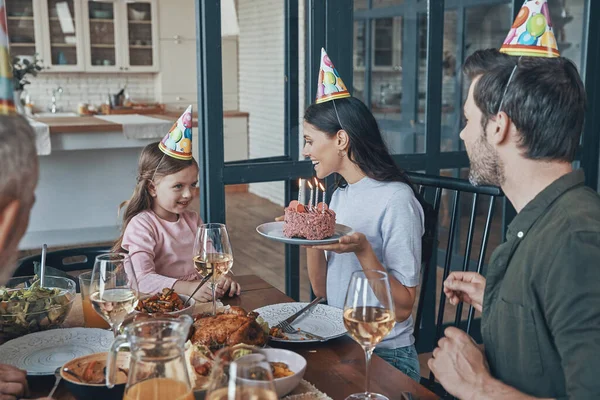 Happy family celebrating birthday of little girl while sitting at the dining table at home — Stock Photo, Image
