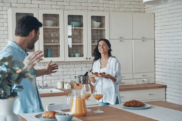 Красивая молодая пара готовит завтрак вместе, проводя время на домашней кухне — стоковое фото