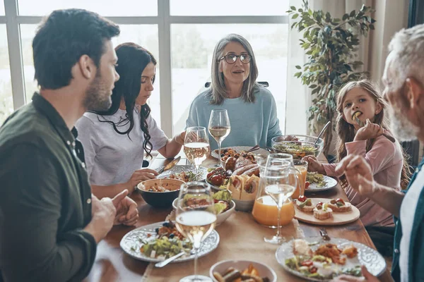 Красивая семья из нескольких поколений, общающаяся и улыбающаяся, обедая вместе — стоковое фото