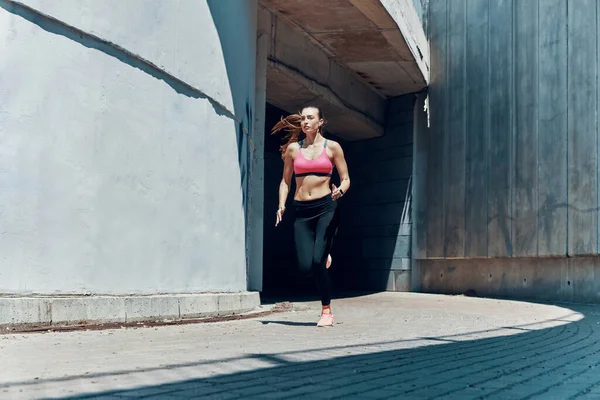 Longitud completa de la hermosa mujer joven en ropa deportiva corriendo al aire libre —  Fotos de Stock