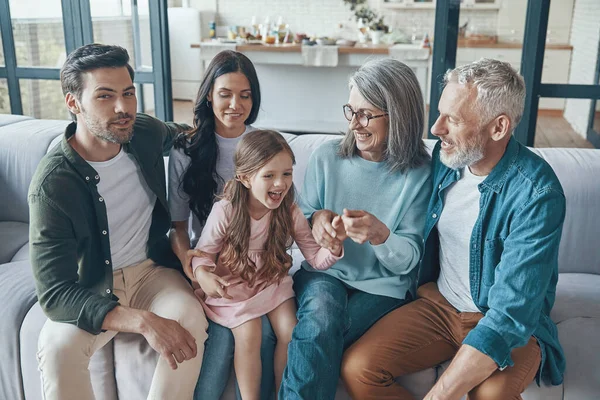 Lycklig familj spenderar tid tillsammans och ler medan du sitter på soffan hemma — Stockfoto