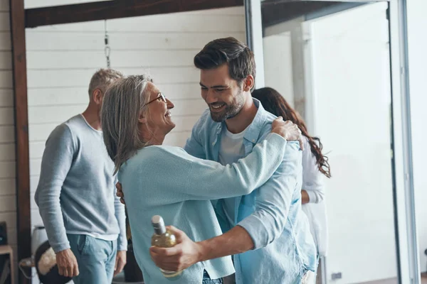 Glada äldre föräldrar träffa unga par inne i huset — Stockfoto