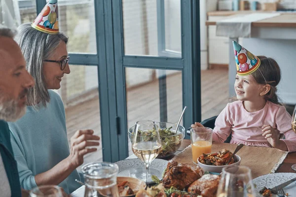 Happy family celebrating birthday of little girl while sitting at the dining table at home — Stock Photo, Image