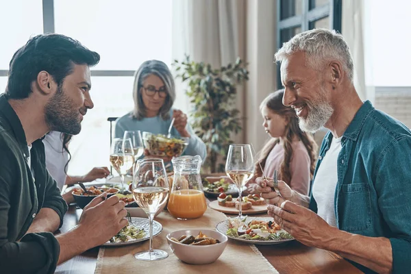 Mutlu çoklu nesil aile yemeği yerken iletişim kuruyor ve gülümsüyor. — Stok fotoğraf