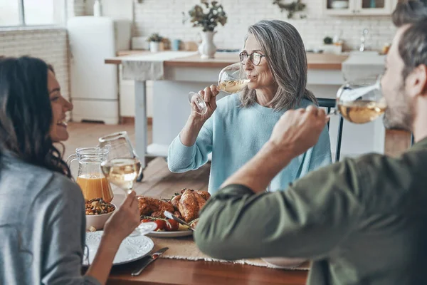 Güzel bir aile birlikte yemek yerken şarap içip gülümsüyor.