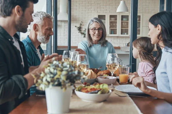 Feliz familia multi-generación comunicándose y sonriendo mientras cenan juntos —  Fotos de Stock