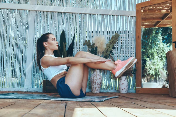 Seitenansicht der schönen jungen Frau in Sportkleidung, die auf der Terrasse trainiert — Stockfoto