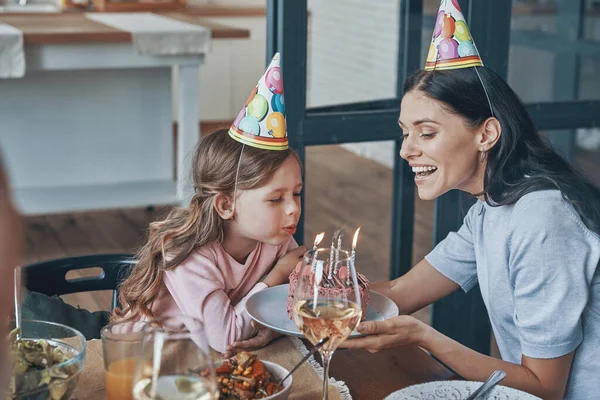 Felice bambina che soffia candele sulla torta di compleanno mentre cena con la famiglia — Foto Stock
