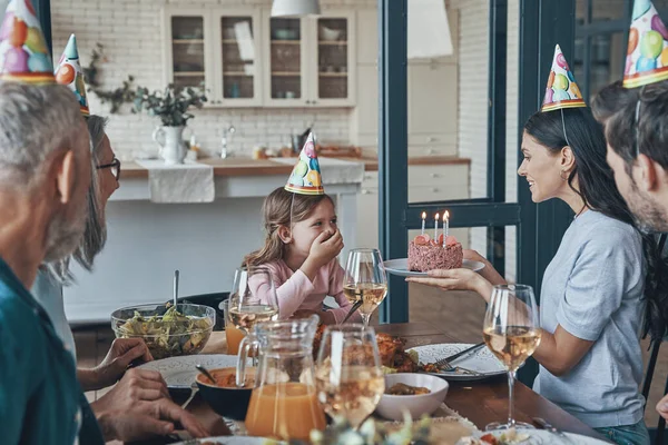 Felice famiglia festeggia il compleanno della bambina mentre si siede al tavolo da pranzo a casa — Foto Stock