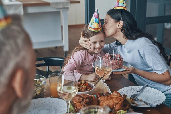 Família feliz comemorando aniversário da menina enquanto se senta na mesa de jantar em casa — Fotografia de Stock