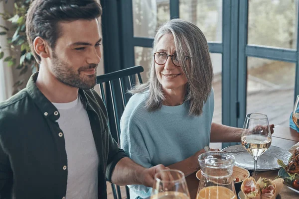 Happy senior mother and son smiling while having dinner together — Stock Photo, Image