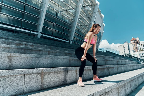 Longitud completa de la joven confiada en ropa deportiva de pie al aire libre —  Fotos de Stock