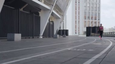 Spor elbiseli, kendinden emin genç bir kadın açık havada koşuyor.