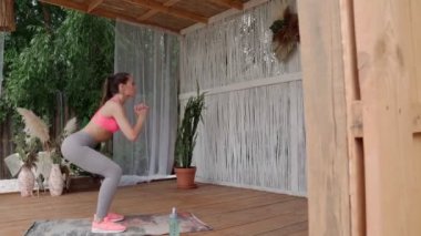 Terasta çömelmiş spor elbiseli güzel bir genç kadın.