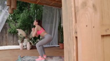 Terasta çömelmiş spor elbiseli güzel bir genç kadın.