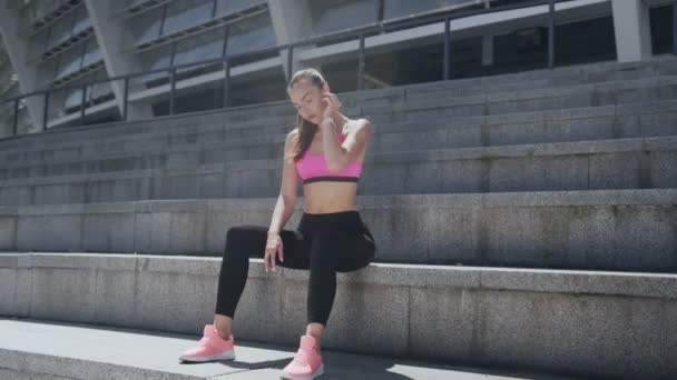 Уверенная молодая женщина в спортивной одежде проверяет свои умные часы — стоковое видео