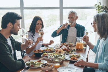 Modern nesil aile birlikte yemek yerken şarap içiyor.