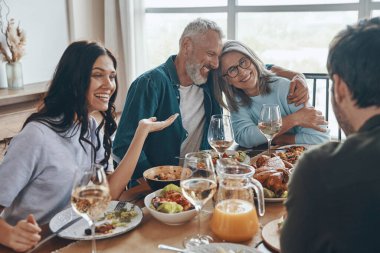 Mutlu çoklu nesil aile yemeği yerken iletişim kuruyor ve gülümsüyor.