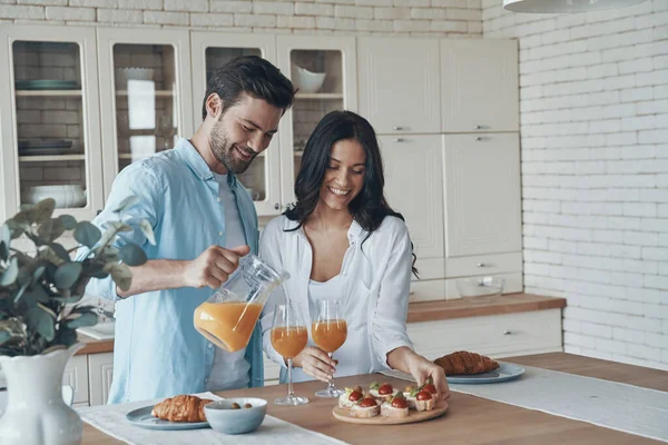 Bella giovane coppia che prepara la colazione insieme mentre trascorre del tempo in cucina domestica — Foto Stock