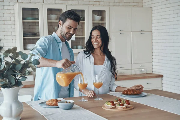 Pareja joven despreocupada preparando el desayuno juntos mientras pasan tiempo en la cocina doméstica —  Fotos de Stock