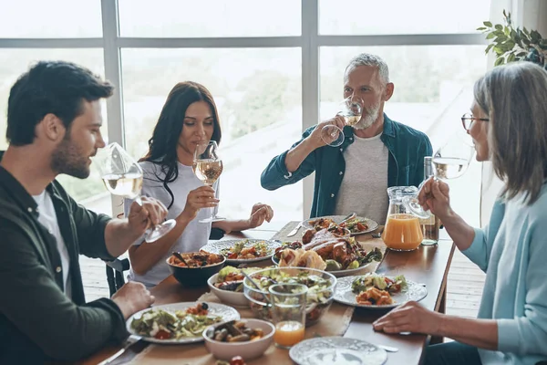 Moderna familia multi-generación bebiendo vino mientras cenan juntos —  Fotos de Stock