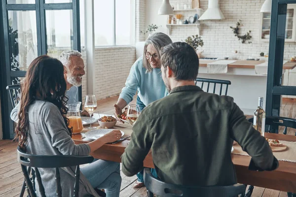 Flergenerationsfamilj som kommunicerar och ler när de äter middag tillsammans — Stockfoto
