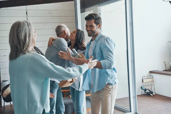 Smiling senior parents meeting young couple inside the house — Stock Photo, Image