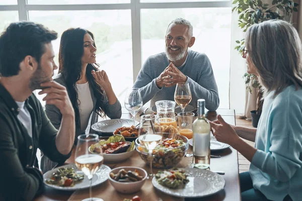 Happy multi-generation family communicating and smiling while having dinner together — Stock Photo, Image