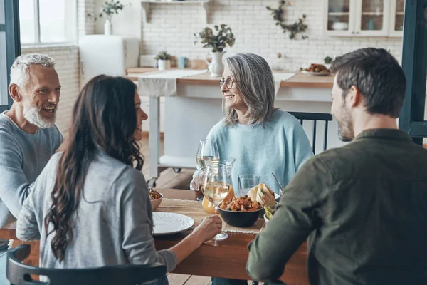 Glad flergenerationsfamilj som kommunicerar och ler samtidigt som de äter middag tillsammans — Stockfoto