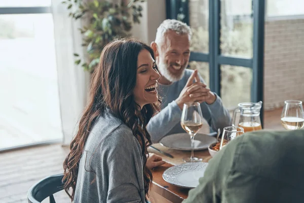 Família feliz comunicando e sorrindo enquanto jantam juntos — Fotografia de Stock