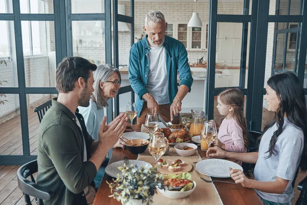 Happy multi-generation family communicating and smiling while having dinner together — Stock Photo, Image