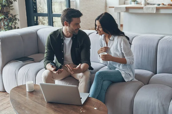 Knap jong tonen zijn vriendin smartphone en glimlachen terwijl zitten op de bank — Stockfoto