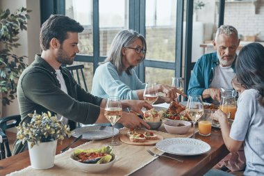 Mutlu çoklu nesil aile yemeği yerken iletişim kuruyor ve gülümsüyor.