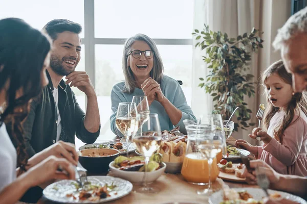 Mutlu çoklu nesil aile yemeği yerken iletişim kuruyor ve gülümsüyor.