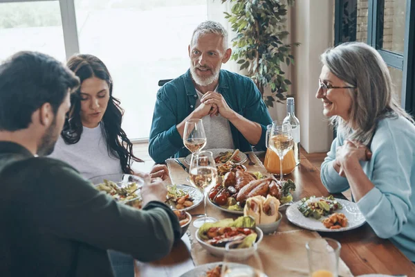 Bela família de várias gerações desfrutando de delicioso jantar enquanto está sentado no apartamento moderno — Fotografia de Stock