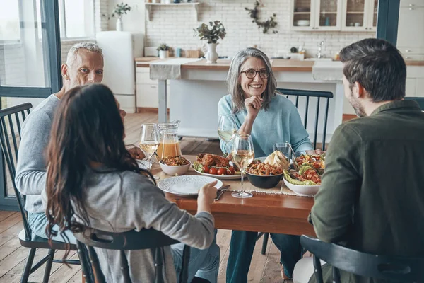 Mutlu çoklu nesil aile yemeği yerken iletişim kuruyor ve gülümsüyor.