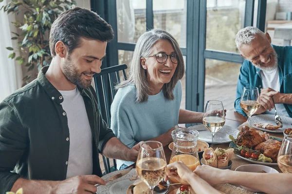 Счастливая семья из нескольких поколений, общающаяся и улыбающаяся во время совместного ужина — стоковое фото