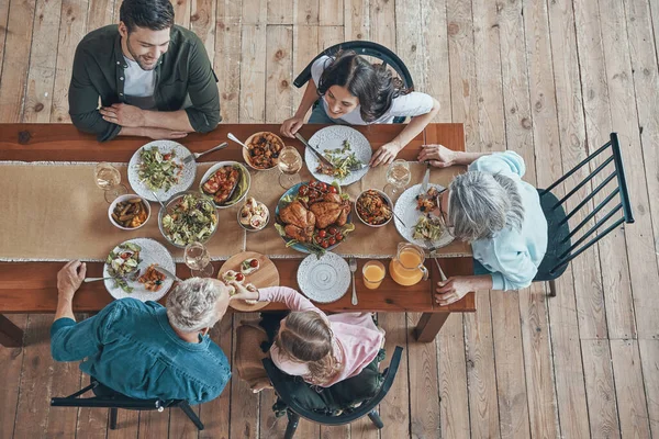 Top view of multi-generation family communicating and smiling while having dinner together — Stock Photo, Image