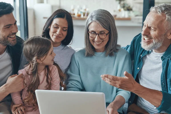 Modern familj tillbringar tid tillsammans och ler medan du sitter på soffan hemma — Stockfoto