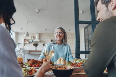 Mutlu çoklu nesil aile yemeği yerken iletişim kuruyor ve gülümsüyor.