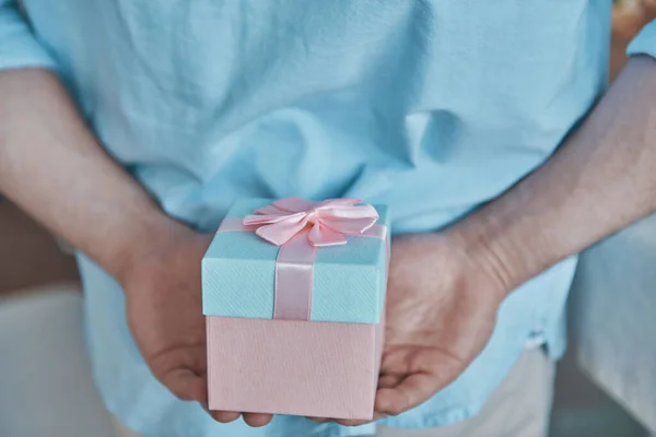 Närbild av man som håller presentförpackning bakom ryggen — Stockfoto