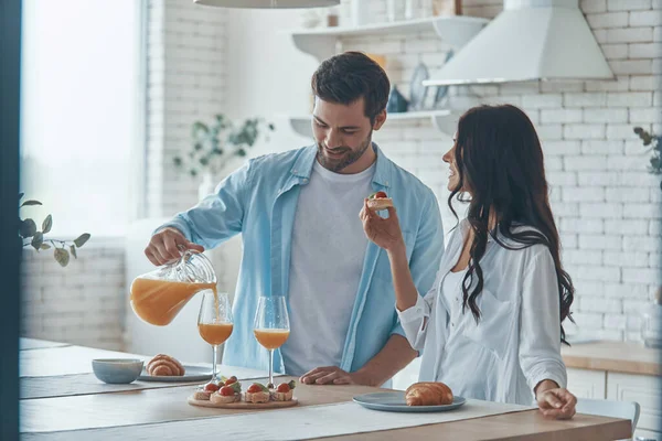 Bella giovane coppia che prepara la colazione insieme mentre trascorre del tempo in cucina domestica — Foto Stock