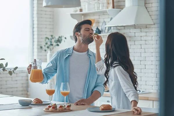 Gyönyörű fiatal pár élvezi a reggelit együtt, miközben időt tölt a hazai konyhában — Stock Fotó