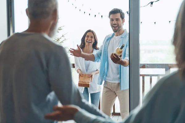 Glückliche Senioren treffen junges Paar im Haus — Stockfoto