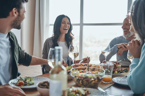 Glückliche Mehrgenerationenfamilie kommuniziert und lächelt beim gemeinsamen Essen — Stockfoto